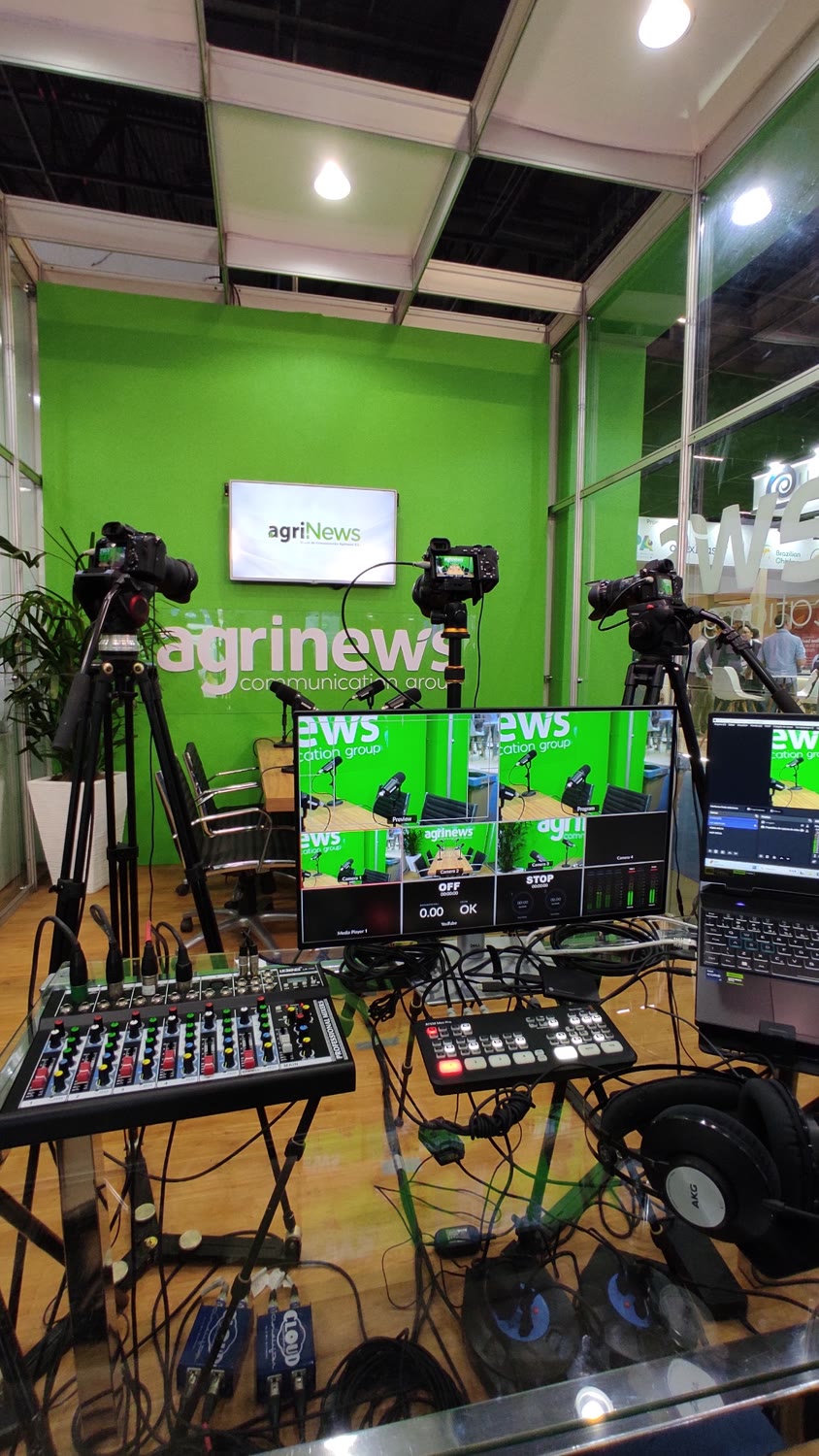 Podcast itinerante montado em estande de evento, com câmeras e mesa de corte